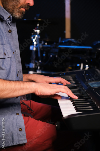 Musician man playing keyboard synthesizer piano in a recording studio. Music production. © Ladanifer