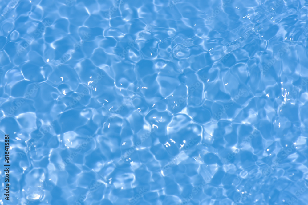 Blue water with ripples on the surface. Defocus blurred transparent blue colored clear calm water surface texture with splashes and bubbles. Water waves with shining pattern texture background.