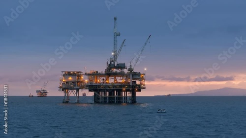 Large illuminated oil drilling rig with several ships on the background. USA. Offshore facility for extraction of oil and gas in San Pedro Channel at dawn. High quality 4k footage photo
