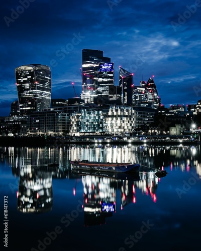 Photography the city skyline of london lit up by the moonlight, with a boat in the