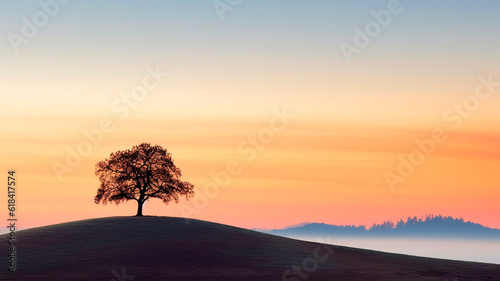 A silhouette of a lone tree on a hill at sunrise.