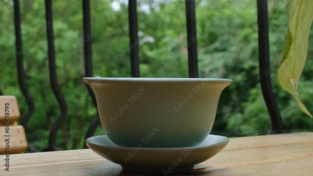 Hot green tea in ceramic cup, close up slow motion shot. Light green color. Tea on the terrace. Hot green tea in ceramic cup, close up slow motion shot. Light green color. Tea on the terrace.