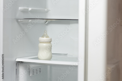 Bottle feeding full of milk on lower shelf of refrigerator