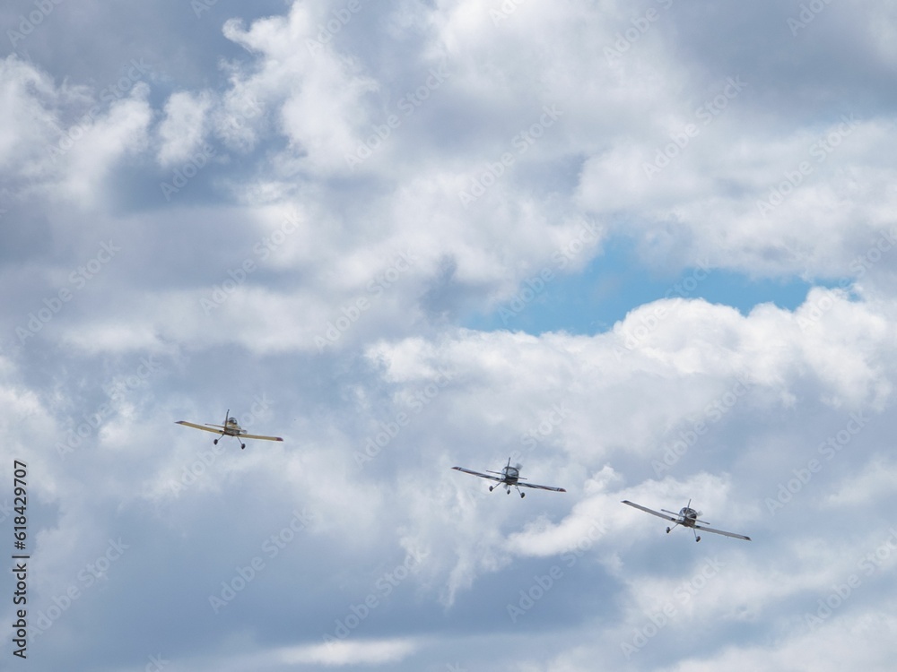 View of airplanes soaring in formation over a landscape of rolling hills and cloudy skies