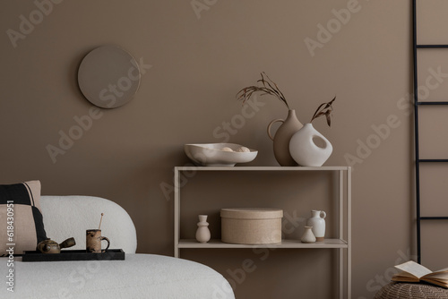 Minimalist composition of living room interior with boucle sofa, beoige rack, stylish vases with dried flowers, black ladder, brown wall, box and personal accessories. Home decor. Template.
