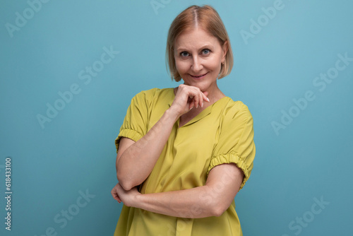 attractive 50s blonde woman in yellow t-shirt on blue background