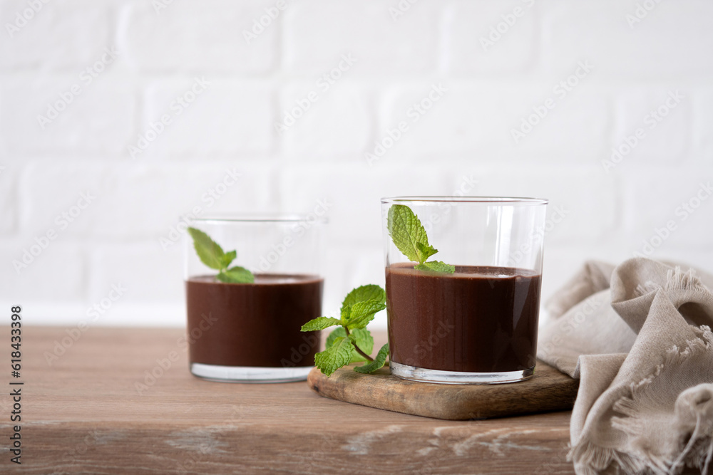 Chocolate mousse dessert garnished with mint leaf on wooden table and white background Chocolate mousse dessert garnished with mint leaf on wooden table and white background