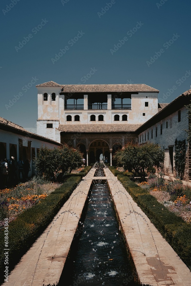 Grand outdoor building with a  fountain surrounded by a vibrant flower garden in Alhambra, Spain