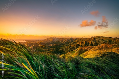 A beautiful sunset over a mountain range, with lush grass and vibrant colors, Guam
