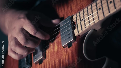 Closeup of a person playing on the bass guitar on the dark background
