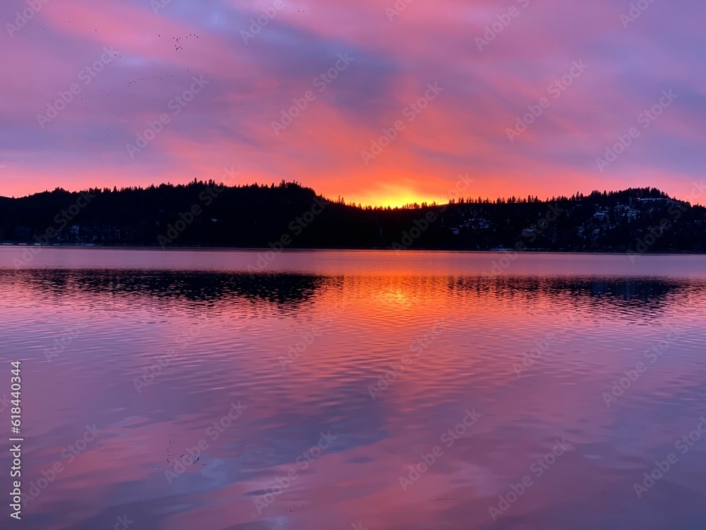 Picturesque lake surrounded by lush green foliage highlighted by a golden sunrise Picturesque lake surrounded by lush green foliage highlighted by a golden sunrise