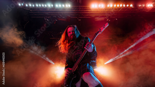 Rock and roll concert. Artistic, expressive man with long hair playing guitar and making performance, emotionally singing. Concept of music, performance, art, talent, nightlife, joy, party, lifestyle