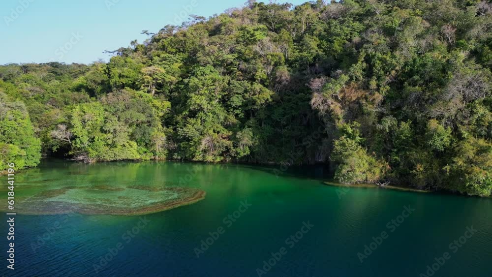 Aerial of a lake surrounded by green forests and mountains on a sunny day Aerial of a lake surrounded by green forests and mountains on a sunny day