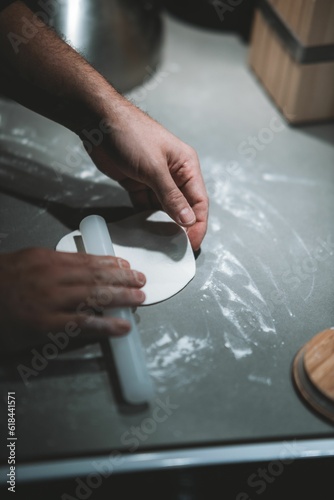 Senior Caucasian male using a rolling pin to flatten a piece of dough on a wooden counter