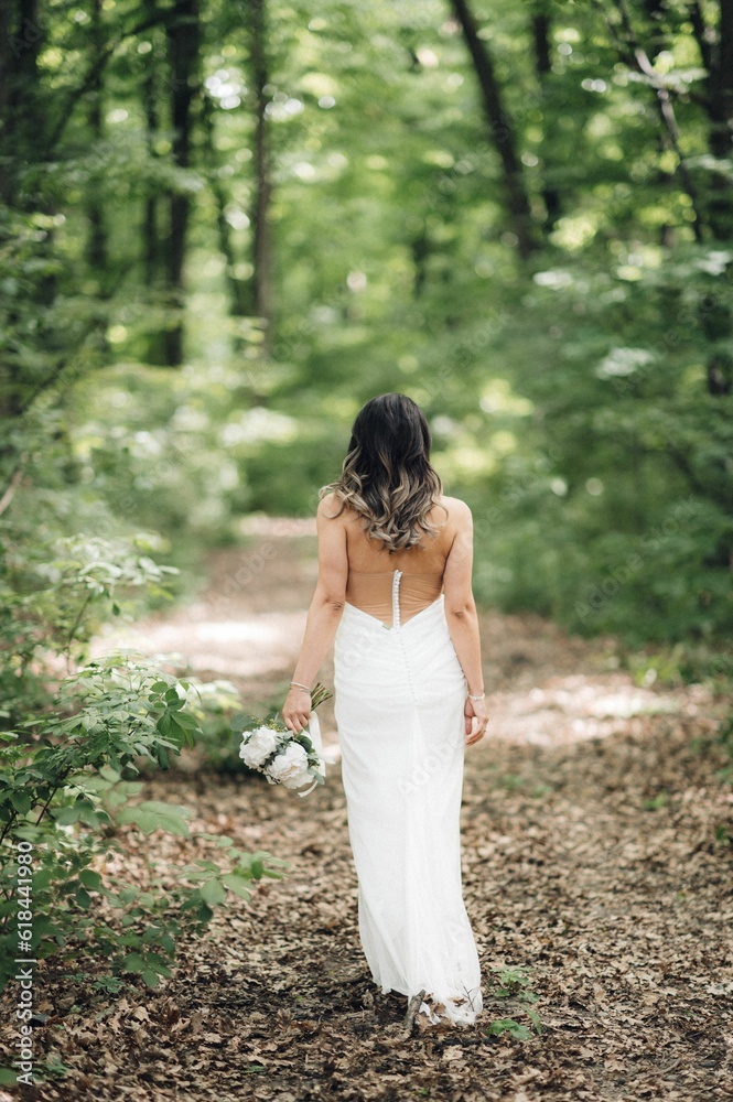 Bride holding a bouquet walking through a lush forest. Bride holding a bouquet walking through a lush forest.