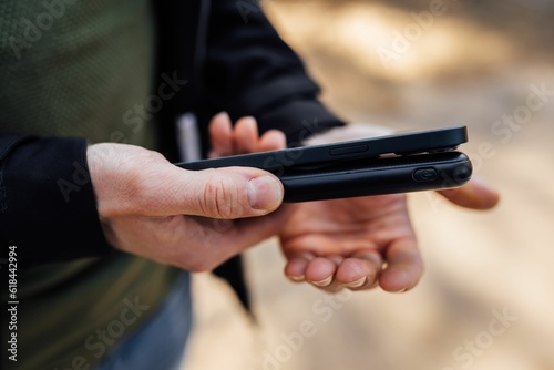 Closeup of the hands of a person holding a smartphone and a wireless phone charger