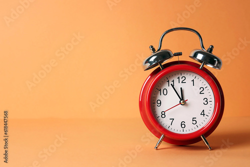 Retro red alarm clock with five minutes to twelve o'clock.