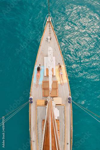 Aerial, ocean and women with phone on boat relax for cruise, luxury sailing and transport on sea. Social media, travel and female people on yacht for tropical journey, sunbathing and tourism on water