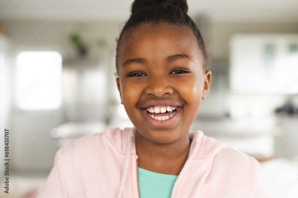 Portrait of happy african american girl wearing pink hoodie, smiling at home Portrait of happy african american girl wearing pink hoodie, smiling at home