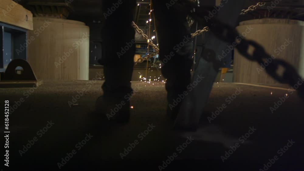 Professional worker welding metal with flames falling on the ground at a workplace Professional worker welding metal with flames falling on the ground at a workplace