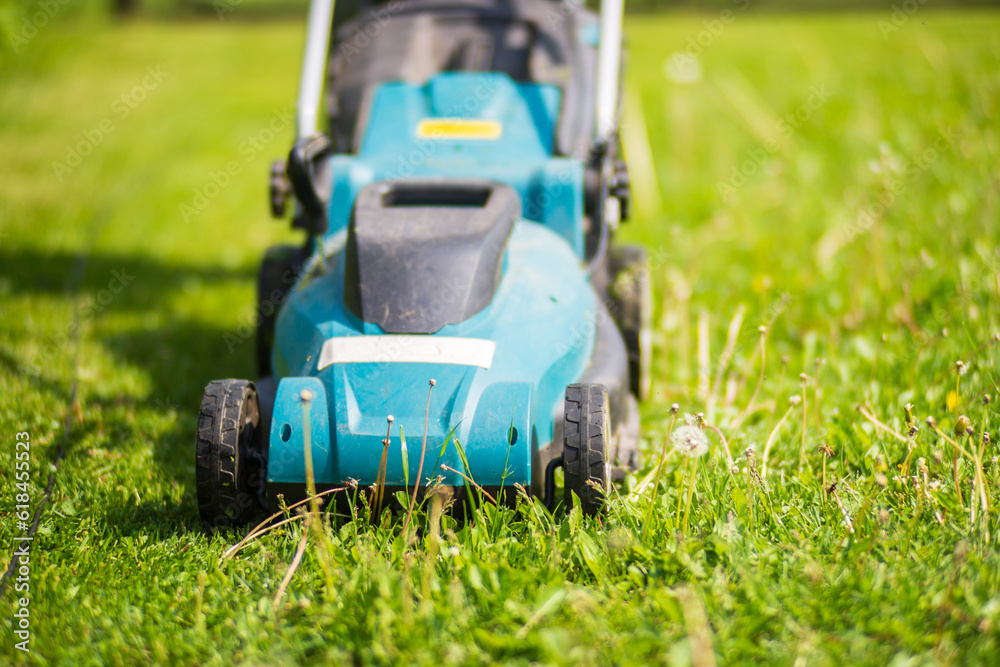 Lawn mover on green grass in modern garden or backyard. Machine for cutting lawns. Gardening care tools and equipment Lawn mover on green grass in modern garden or backyard. Machine for cutting lawns. Gardening care tools and equipment