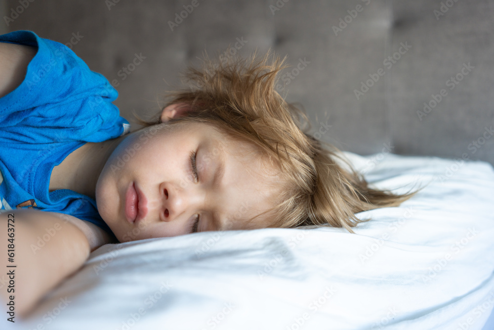 Boy sleeping in pajamas on white bed Boy sleeping in pajamas on white bed