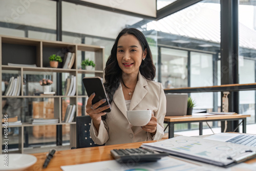 Free Download Pretty young business woman sitting on workplace. Smiling business woman. young business woman on the phone at office. Business woman texting on the phone and working on laptop - GFXLoad