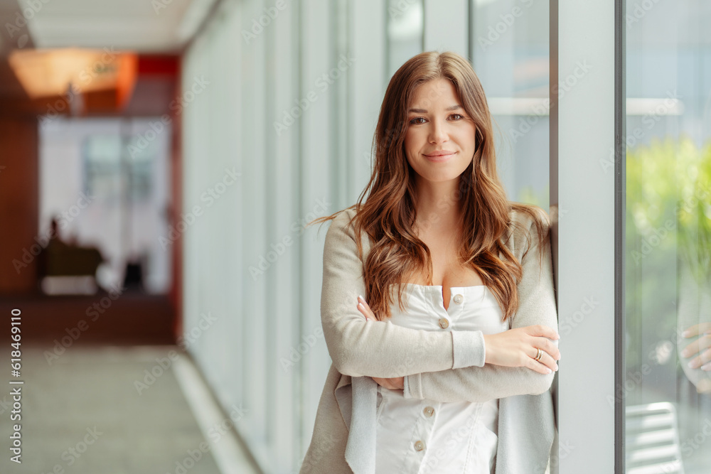 Portrait of beautiful smiling businesswoman with arm crossed standing in modern office. Confident manager, worker wearing stylish clothes looking at camera indoors. Successful business, career concept Portrait of beautiful smiling businesswoman with arm crossed standing in modern office. Confident manager, worker wearing stylish clothes looking at camera indoors. Successful business, career concept