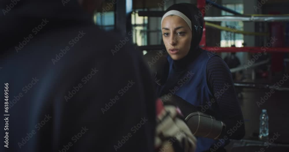 Portrait of Young Determined Arab Woman with Hijab Practicing Boxing in Gym with her Coach. Strong Muslim Female Boxer Working Out and Exercising, Throwing Punches and Preparing for Competition Portrait of Young Determined Arab Woman with Hijab Practicing Boxing in Gym with her Coach. Strong Muslim Female Boxer Working Out and Exercising, Throwing Punches and Preparing for Competition