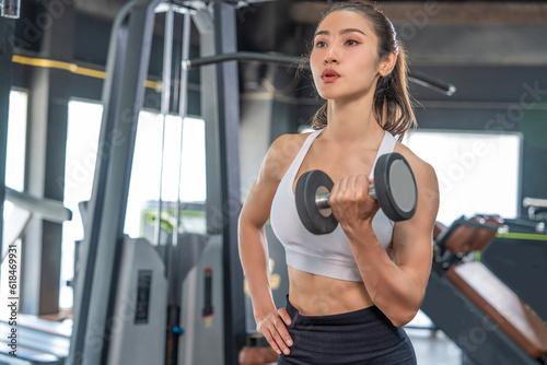 Healthy lifestyle and fitness concept. Asian woman wearing sports bra doing lifting dumbbell weight exercise in sport gym