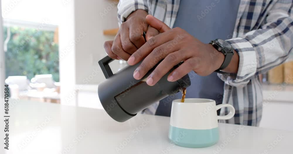 Mid section of african american man making coffee in kitchen, slow motion Mid section of african american man making coffee in kitchen, slow motion