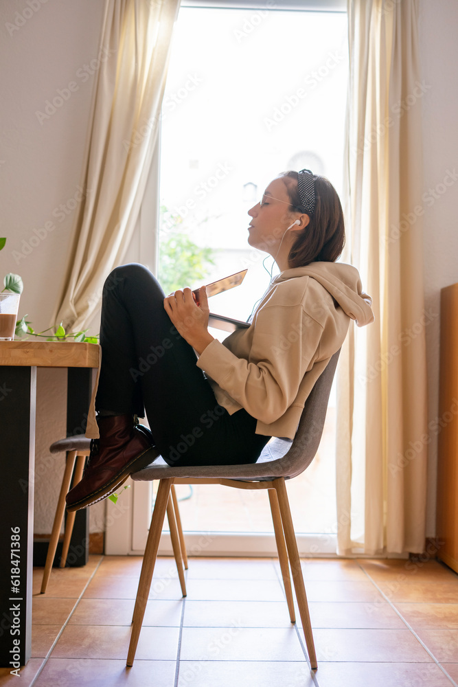girl working at home. Girl with her legs up on the chair and the computer on top of her legs working girl working at home. Girl with her legs up on the chair and the computer on top of her legs working