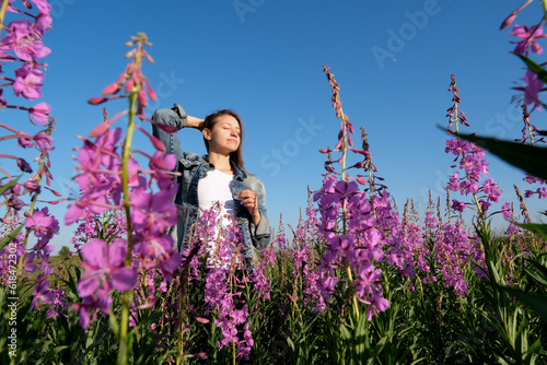 smiling young woman with hat on willow-herb flowers field. happiness, nature, summer, vacation concept