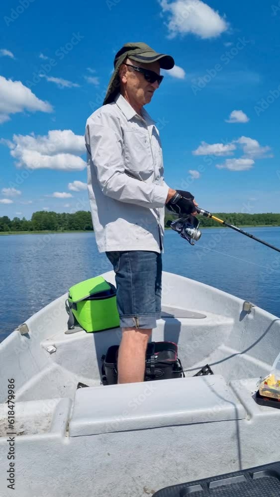senior man fishing from the boat with spinning rod on sunny summer day