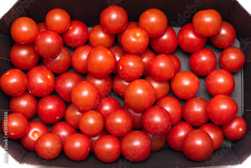 Top view of ripe cherry tomatoes in a cardboard box. © svdolgov