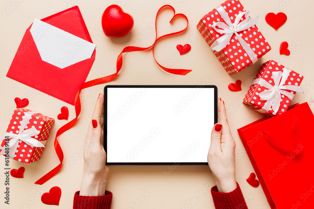 Female hands using a laptop for Valentine day background, gift box and envelope, hearts