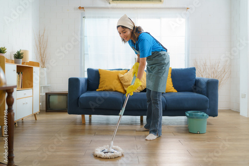 Diligent Asian housewife meticulously mops the living room, epitomizing dedication and determination in maintaining a clean and tidy home.