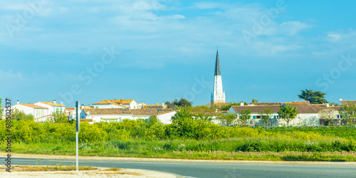 Black and white bell tower of Sainte-Etienne church in Ars-en-Ré, France seen from a countryside road