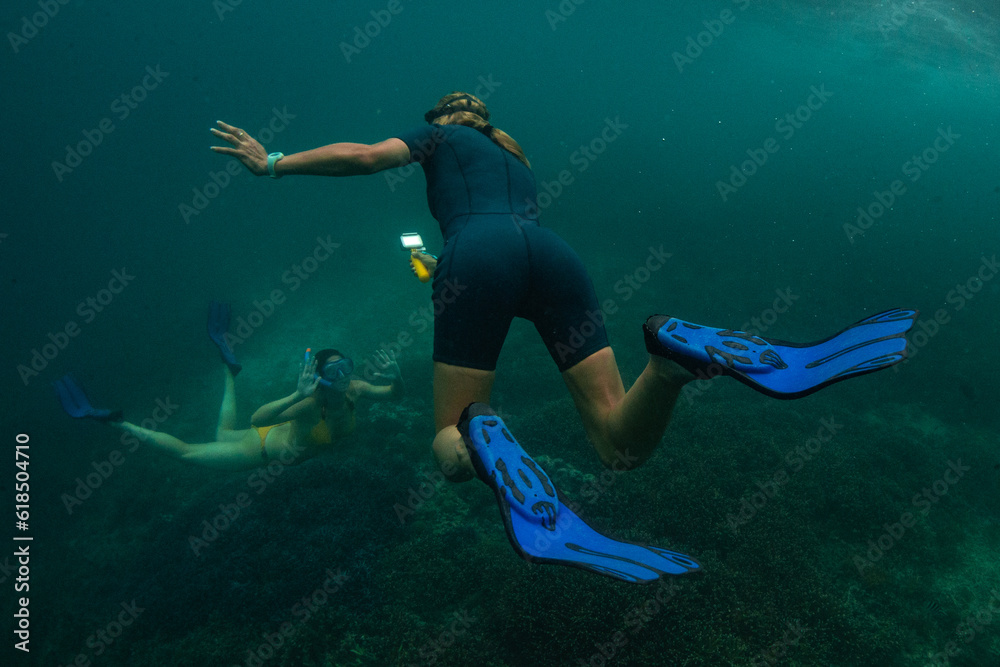 26 March 2019 near island Gilli, Indonesia. Woman swimming underwater with action camera in coral reef and shooting girlfriend
