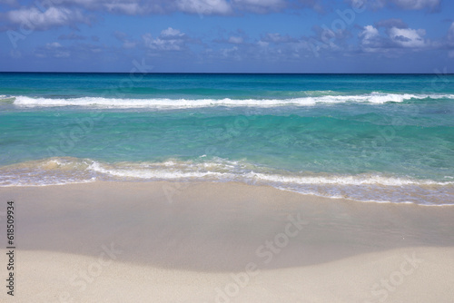 Empty sea beach with white sand  view to azure waves and blue sky with clouds. Caribbean coast  Background for holidays on a paradise nature