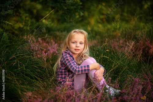 Little blonde girl sitting in heather