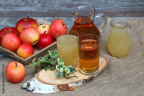 Apfelsaft in Gläsern und Flasche auf einem Holztisch.