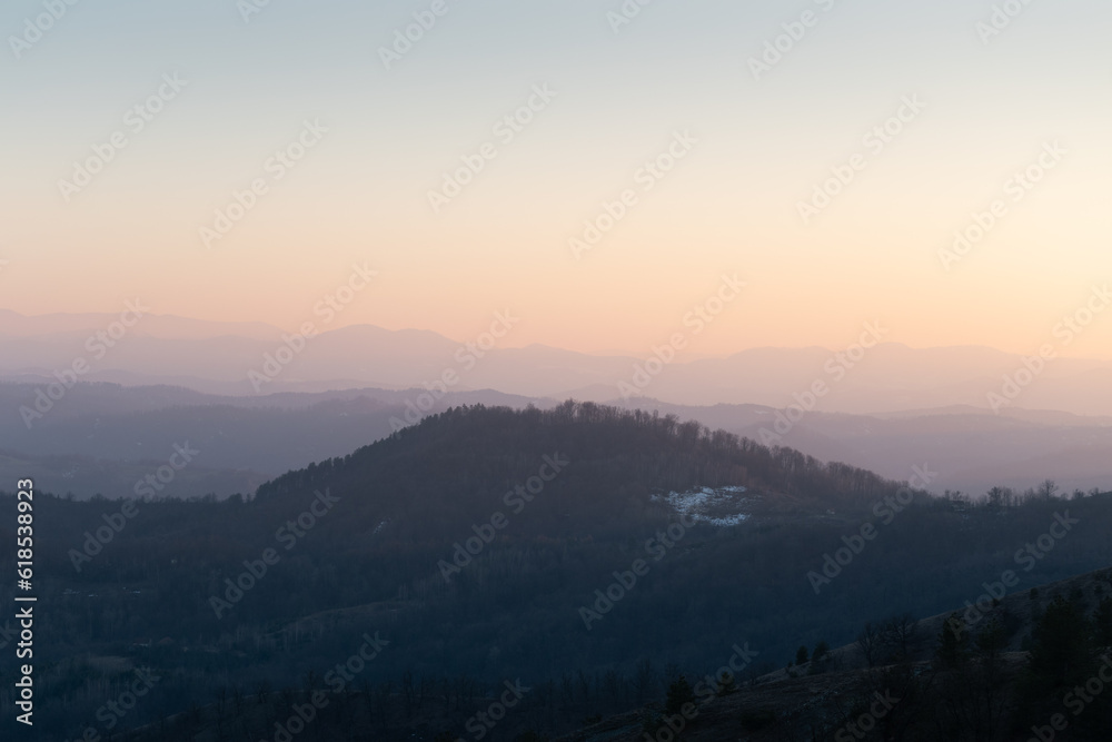 Landscape with hill overgrown in forest against mountain layers fading in distance, view from mountain Ljubic near Prnjavor