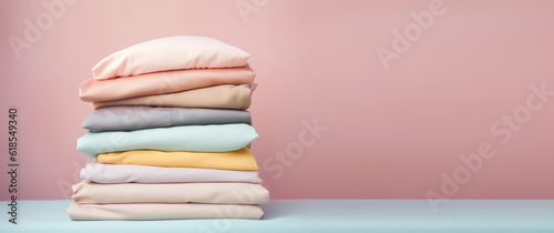 Stack of fresh, clean linens in a pastel palette of colors. Textile cloths stack. Isolated on light pink background with copy space, banner template. Generative AI photo.