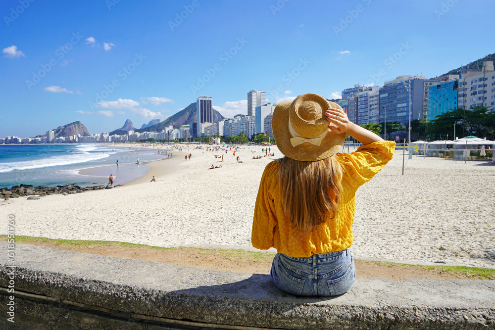 Beautiful young woman sitting on wall enjoying the cityscape of Rio de Janeiro, Brazil