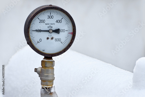 Old frozen pressure gauge on gas pipe in winter.