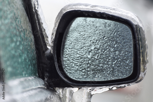 Frozen car with icicles, glass and side doors. Icing vehicle on a winter day after freezing rain in Ukraine. Blurred background.