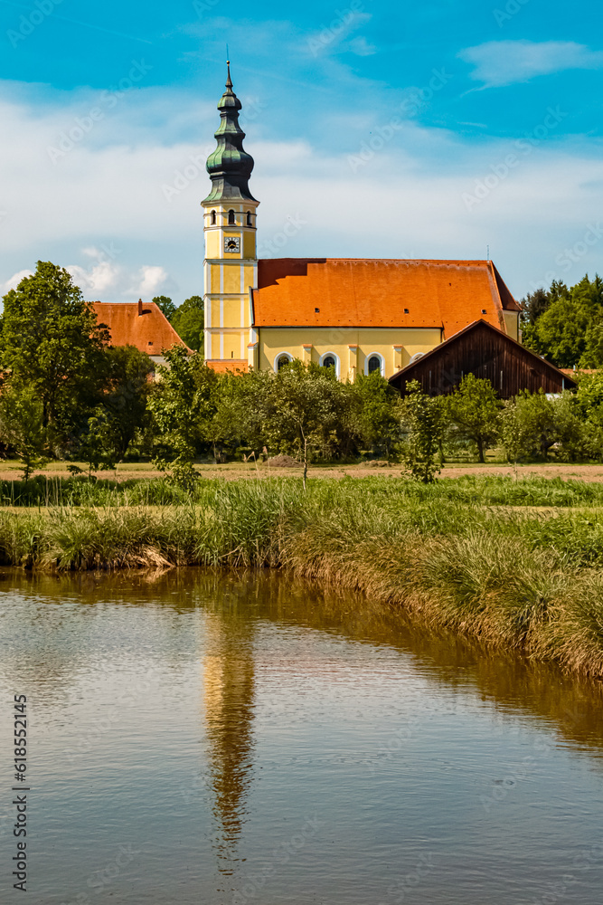Pilgrimage church with reflections in a pond on a sunny summer day at Sammarei, Ortenburg, Passau, Bavaria, Germany