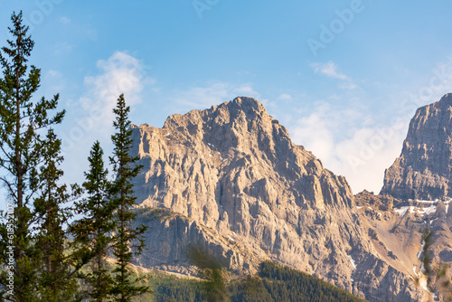 Incredible nature scenery outside of Banff National Park during summer time with iconic Three Sisters in view on sunset, golden hour afternoon. 