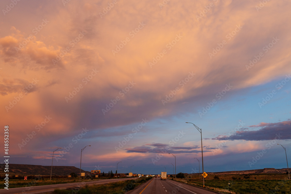 Obraz premium Scenic landscape with highway among mountains and colorful sky at dusk. Blue, orange and purple sky at sunset over the road. Highway 40, Arizona, USA - 06-17-2022